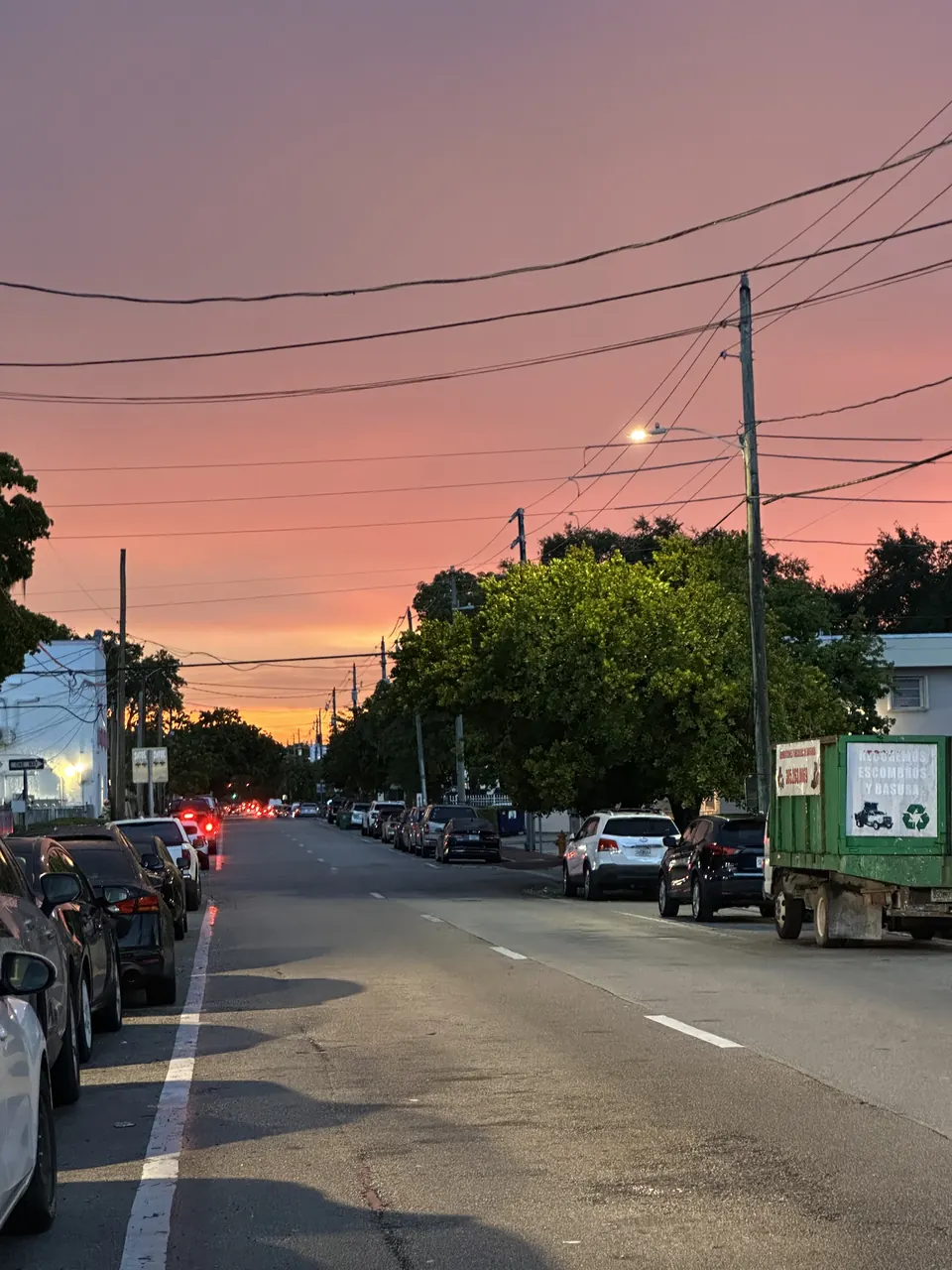 Bir Miami sokağının üzerinde pembe ve turuncu akşam gökyüzü.
