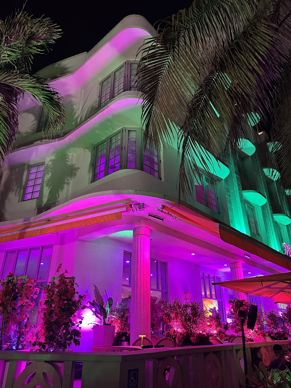 Gece pembe ve yeşil ışıklarla aydınlatılmış bir Miami binası.