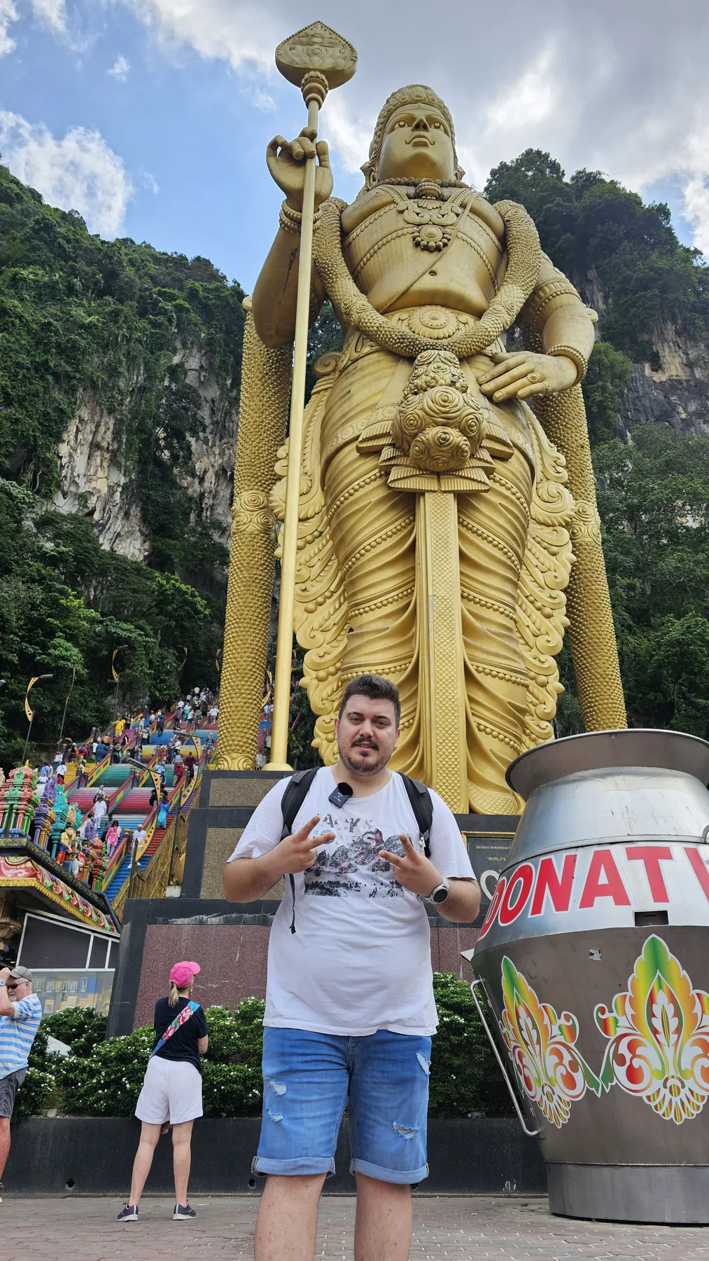Altın renkli heykelin ve renkli merdivenlerin önünde duruyorum.