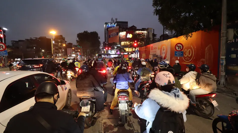 Gece Hanoi trafiğinde yan yana bekleyen motosikletler ve araçlar.